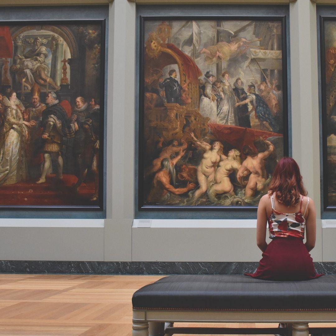 Woman sitting in front of art at a museum. 